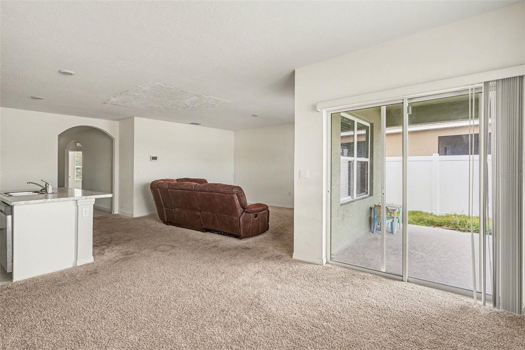 A living room with beige carpet, a brown sofa, and a sliding glass door to a patio — 693 SQUIRES GROVE DRIVE, WINTER HAVEN, FL