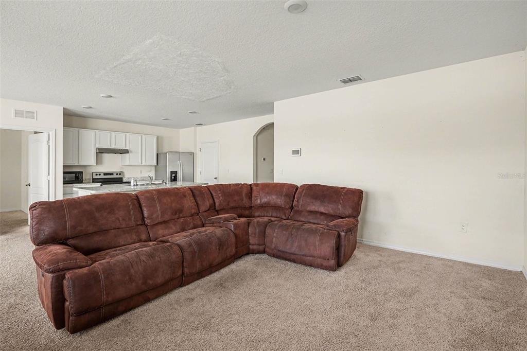 A living room with a large brown sectional sofa faces an open-concept kitchen — 693 SQUIRES GROVE DRIVE, WINTER HAVEN, FL