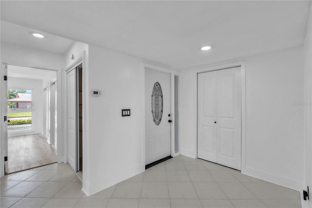 A white-walled entryway features a front door with a decorative glass insert and tiled floors — 6522 11TH AVENUE W, BRADENTON, FL