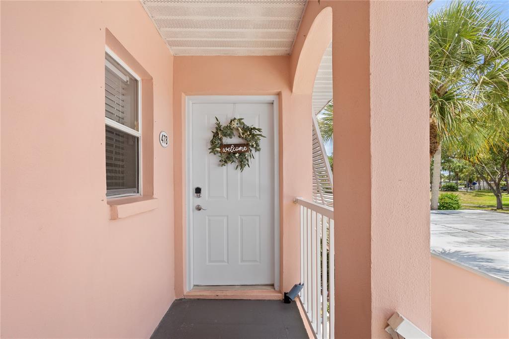 A two-story pink apartment building features an exterior staircase leading to second-floor balconies — 436 CERROMAR LANE UNIT 478, VENICE, FL