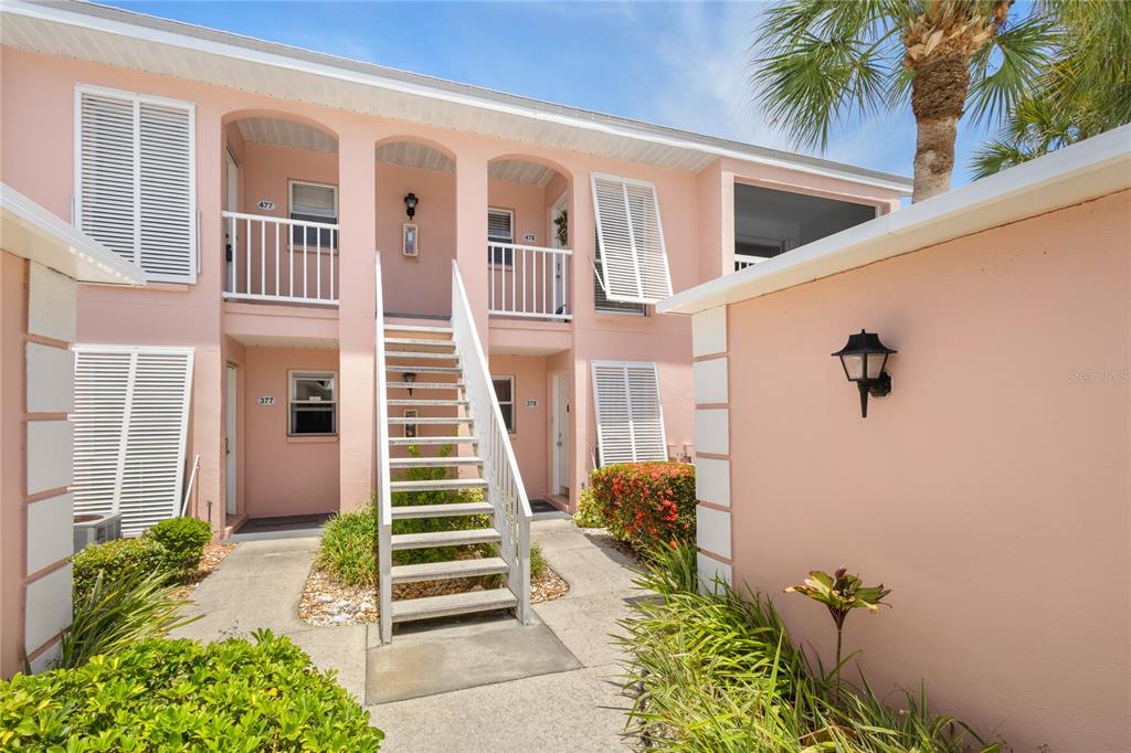 An empty room features vaulted ceilings, wood-look flooring, a chandelier, and sliding glass balcony doors — 436 CERROMAR LANE UNIT 478, VENICE, FL