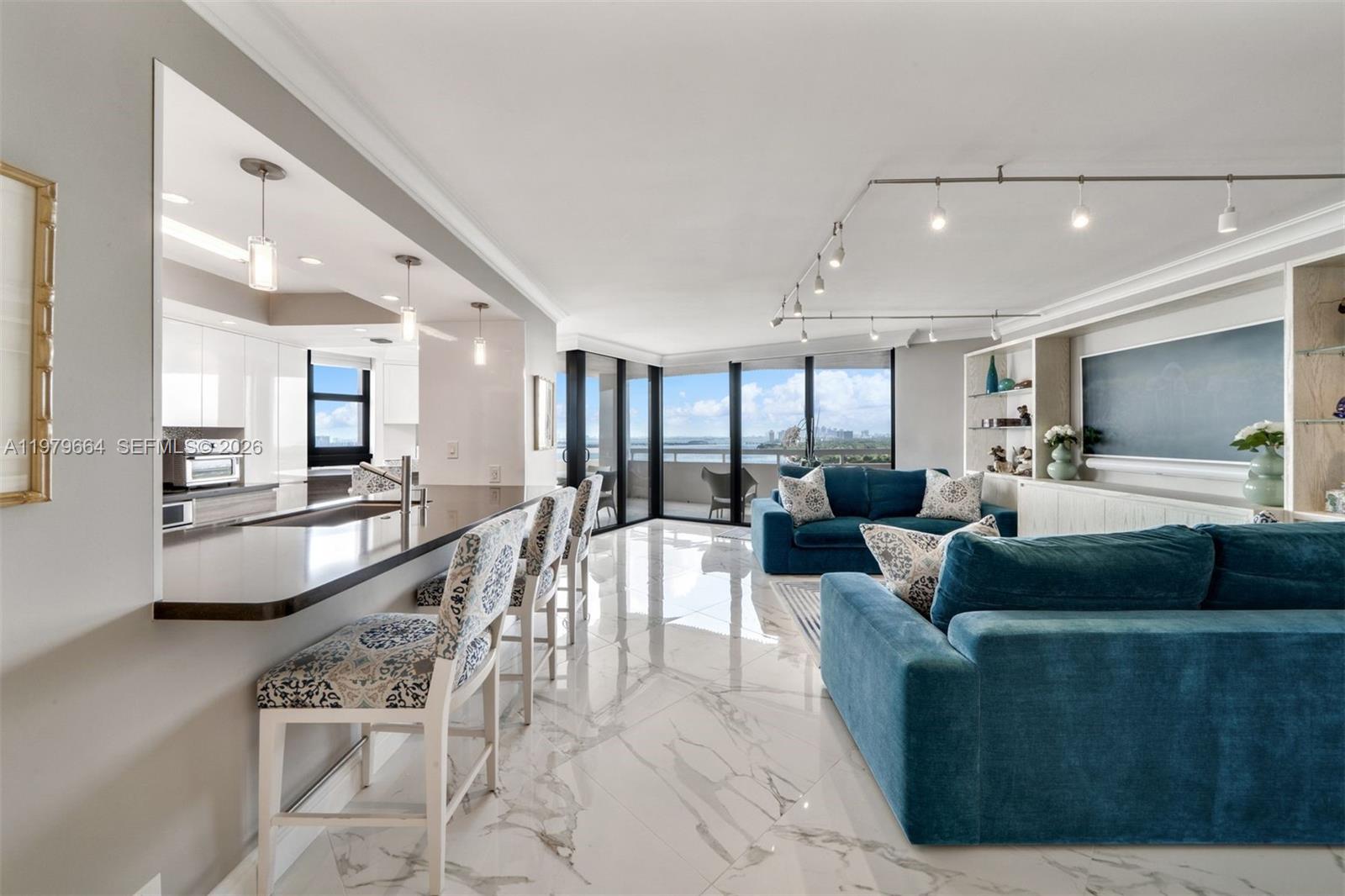 A modern living room and kitchen area features marble floors, blue sofas, and balcony views — 2000 Towerside Ter, Miami FL 33138, MIAMI, FL