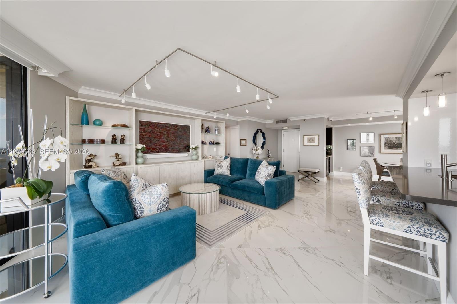 A living room features blue sofas, a glass coffee table, and white marble flooring — 2000 Towerside Ter, Miami FL 33138, MIAMI, FL