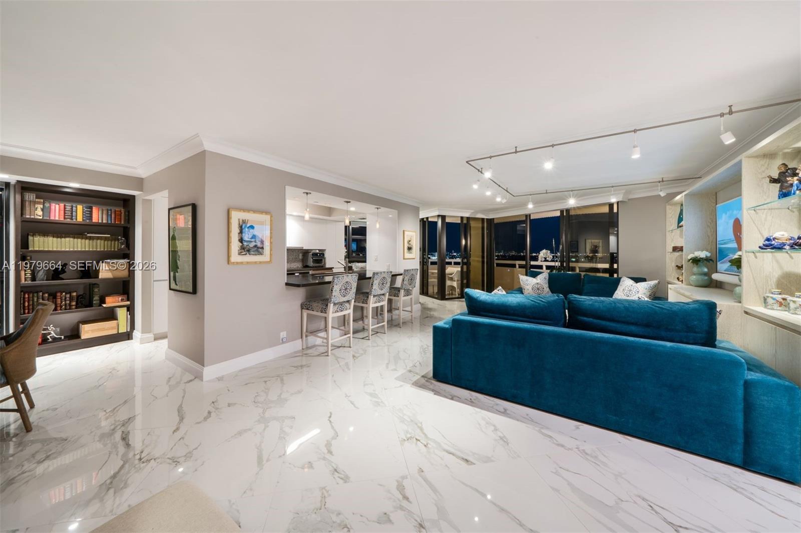 A living room features a blue sectional sofa, marble floors, a bookshelf, and a kitchen bar — 2000 Towerside Ter, Miami FL 33138, MIAMI, FL