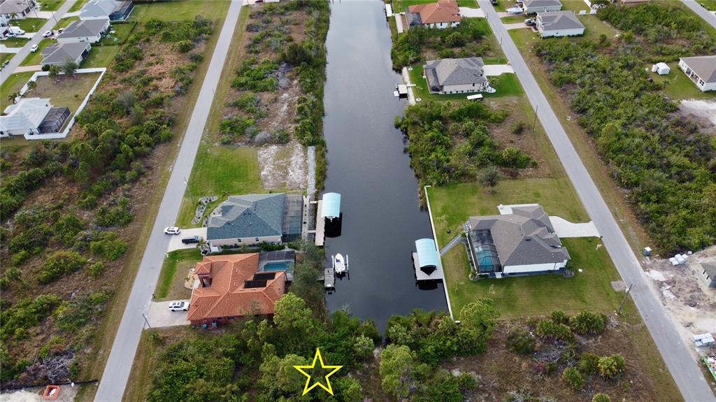 An aerial view shows a canal between two residential streets with houses and boat docks — 10281 ST PAUL DRIVE, PORT CHARLOTTE, FL