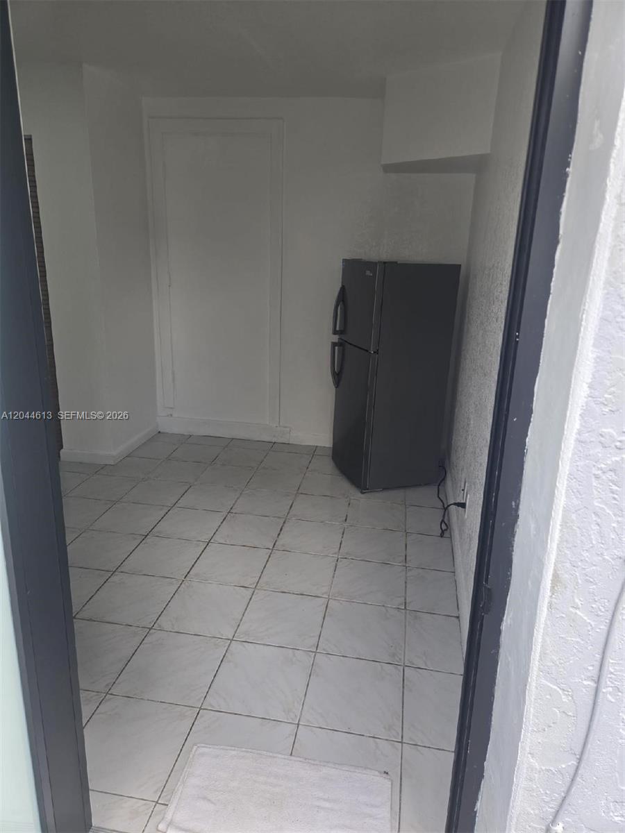 A small, tiled room contains a grey refrigerator against a white wall — 735 SULTAN AVE # 1, Opa-Locka FL 33054, OPA-LOCKA, FL
