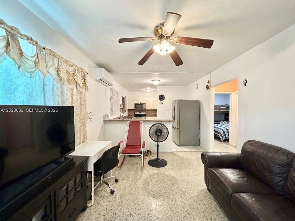 A living room with a ceiling fan, desk, and sofa opens to a kitchen area — 130 NW 16th Ave, Miami FL 33125, MIAMI, FL