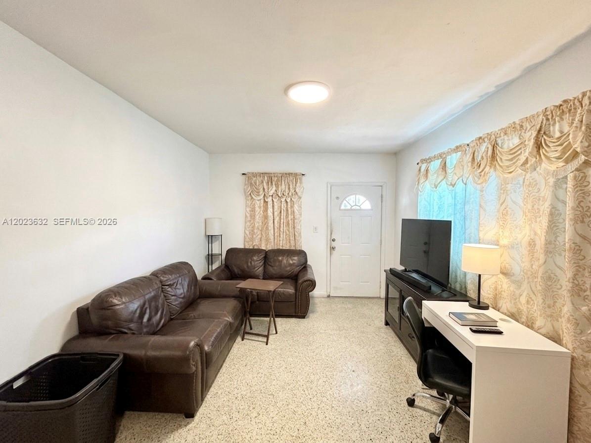 A living room features brown leather sofas, a white desk, and patterned window curtains — 130 NW 16th Ave, Miami FL 33125, MIAMI, FL
