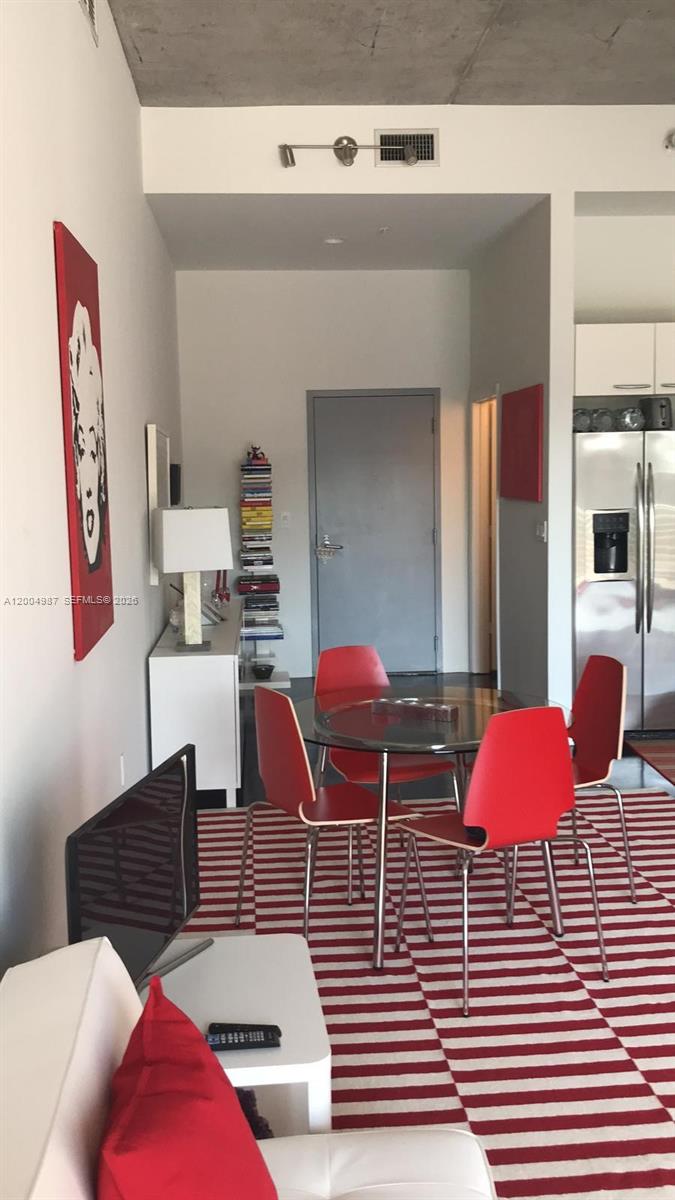 A dining area features a glass table with four red chairs on a striped rug — 2001 Meridian Ave # 426, Miami Beach FL 33139, MIAMI BEACH, FL