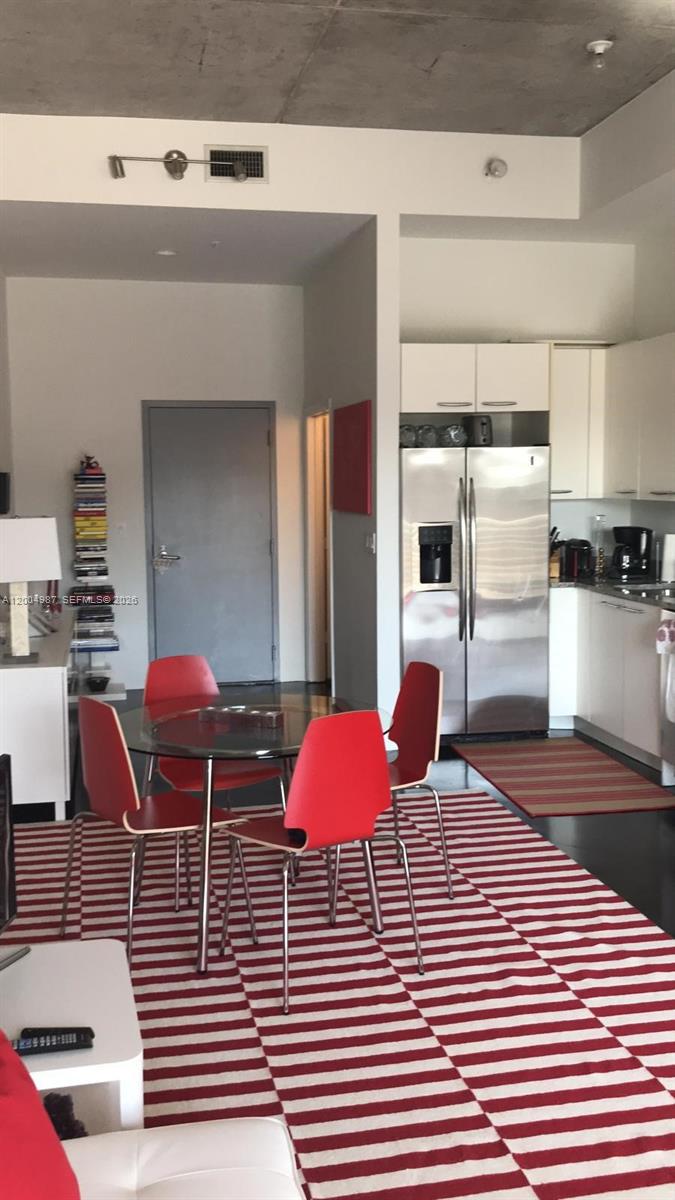A dining area with a glass table and red chairs sits before a modern kitchen — 2001 Meridian Ave # 426, Miami Beach FL 33139, MIAMI BEACH, FL
