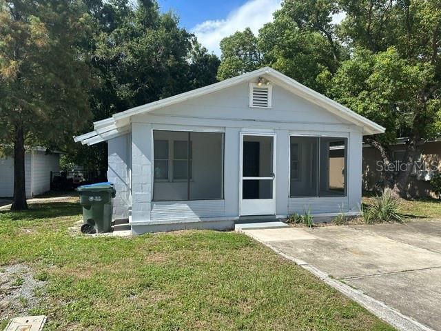 A light blue, single-story house features a screened-in front porch and a concrete driveway — 1010 ROSERY ROAD NW, LARGO, FL