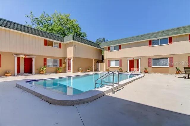 A rectangular swimming pool sits in the courtyard of a two-story tan apartment complex — 300 6TH STREET N UNIT W2, SAFETY HARBOR, FL
