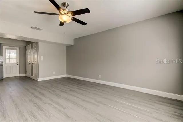 An empty room features light gray wood-look flooring, a ceiling fan, and a white door — 300 6TH STREET N UNIT W2, SAFETY HARBOR, FL