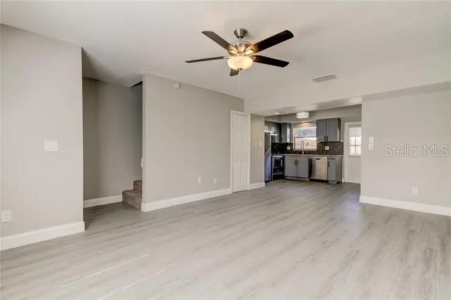 A living area with light wood-look flooring leads to an open kitchen with gray cabinets — 300 6TH STREET N UNIT W2, SAFETY HARBOR, FL