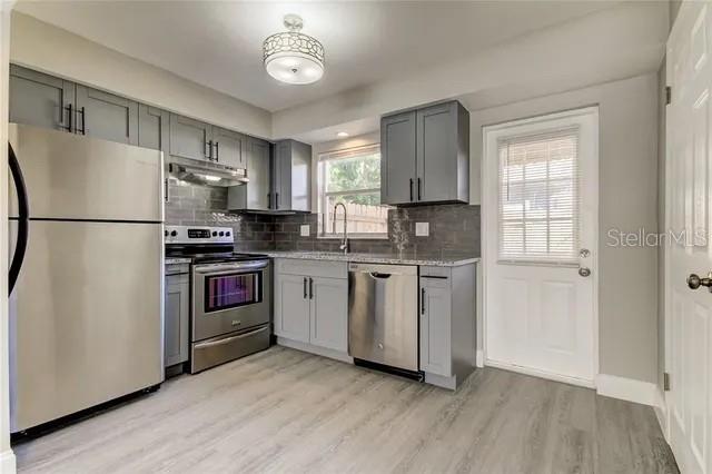 A kitchen features gray cabinets, stainless steel appliances, and light wood-look flooring — 300 6TH STREET N UNIT W2, SAFETY HARBOR, FL