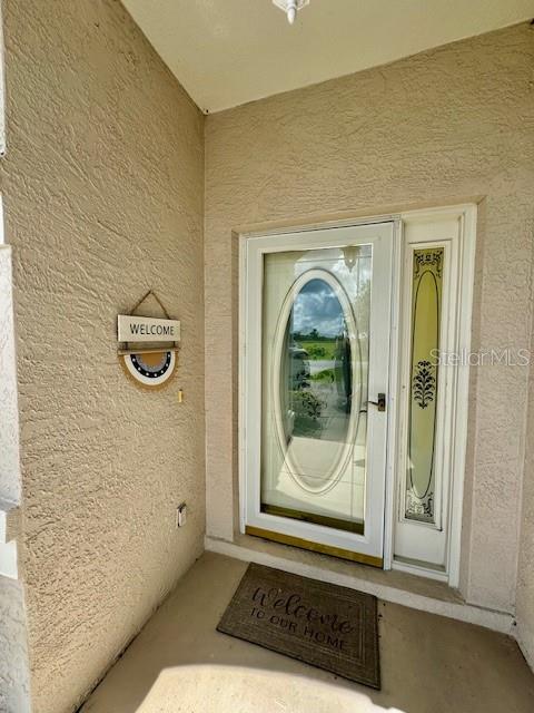 A front entryway features a textured beige wall, a glass-paneled door, and a welcome mat — 2360 NW 53RD AVENUE ROAD, OCALA, FL