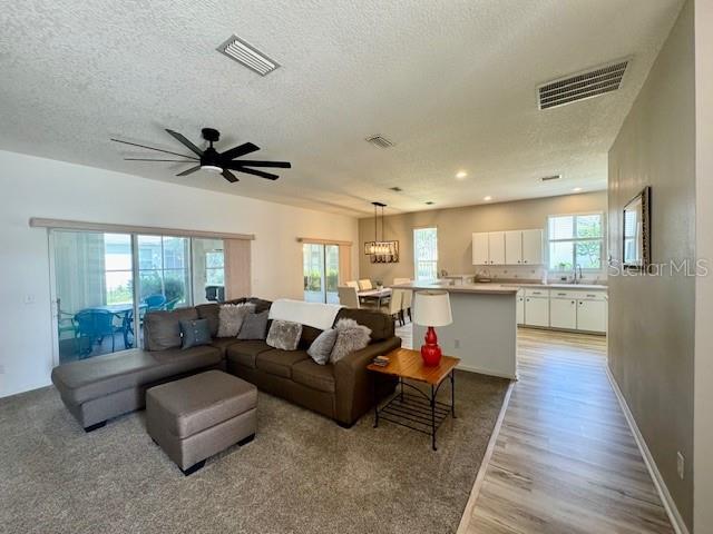 A living room with a sectional sofa and ottoman opens to a kitchen with white cabinets — 2360 NW 53RD AVENUE ROAD, OCALA, FL