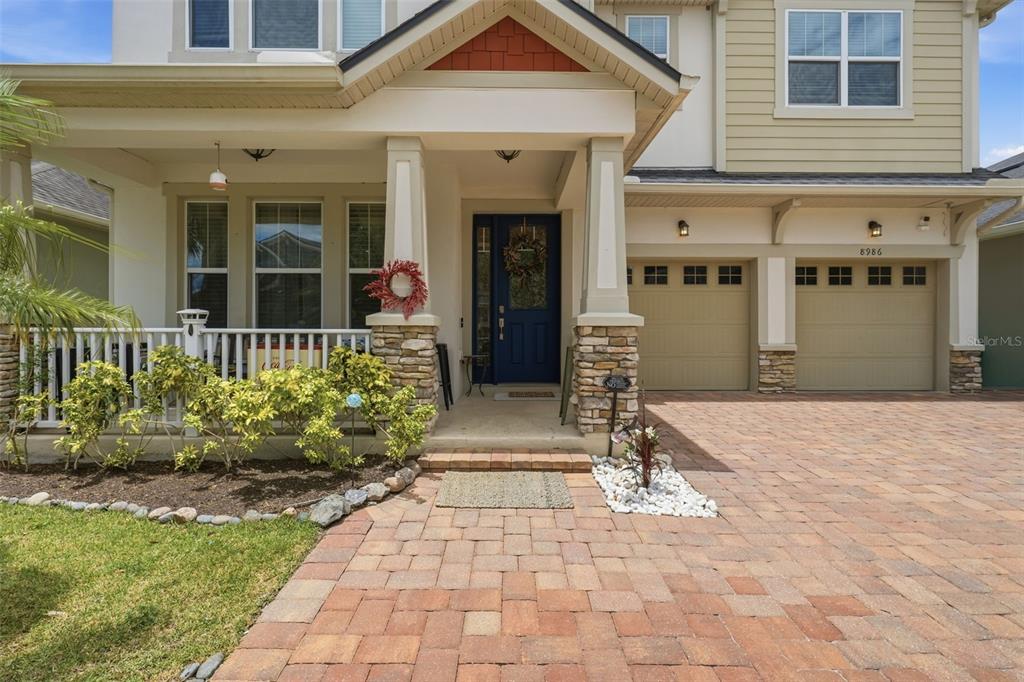 A two-story house features a covered front porch, a brick paver driveway, and a garage — 8986 FULLERWOOD AVENUE, ORLANDO, FL