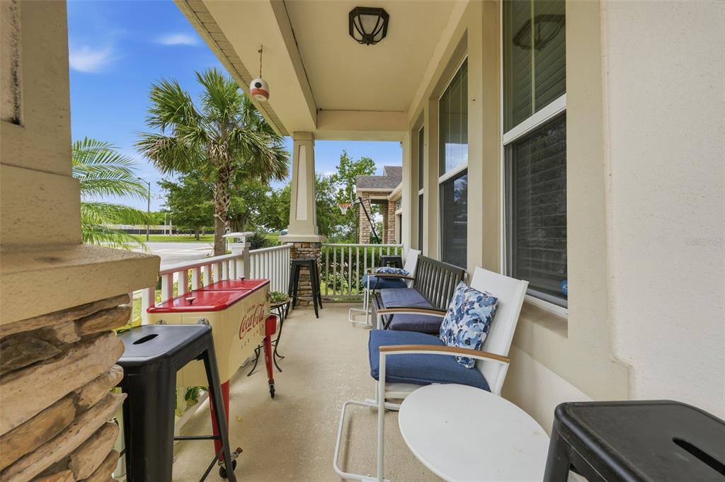 A covered front porch features a red Coca-Cola cooler, outdoor seating, and stone pillar accents — 8986 FULLERWOOD AVENUE, ORLANDO, FL