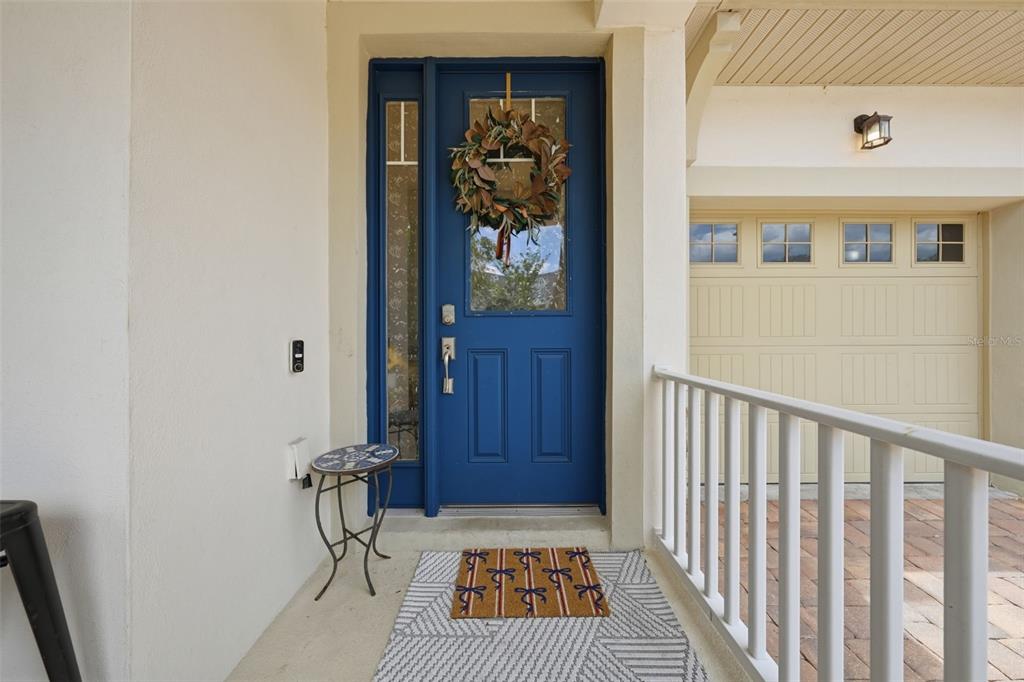 A blue front door with a wreath sits on a porch next to a garage — 8986 FULLERWOOD AVENUE, ORLANDO, FL