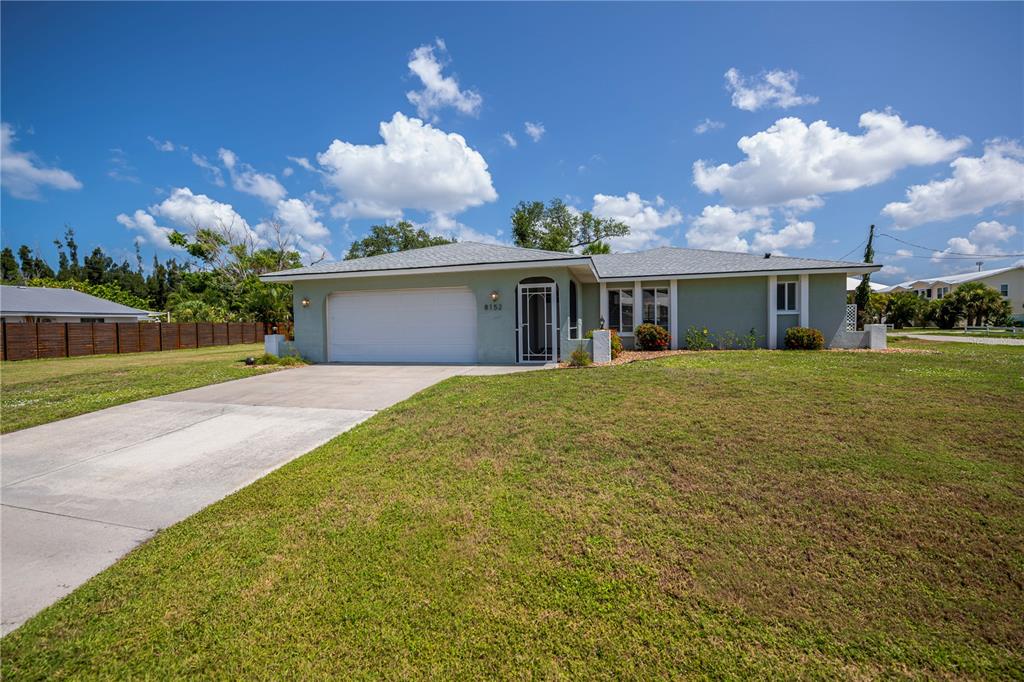 A single-story house with a light green exterior, a two-car garage, and a concrete driveway — 8152 SEASHELL STREET, ENGLEWOOD, FL