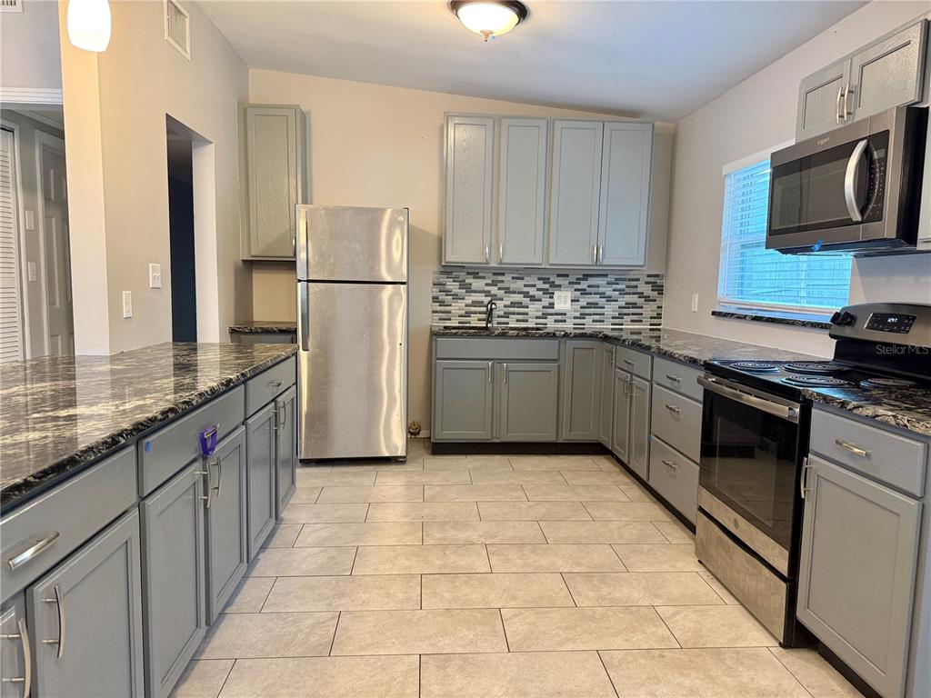A kitchen with grey cabinets, stainless steel appliances, and dark granite countertops — 5801 JUDY DEE DRIVE, ORLANDO, FL