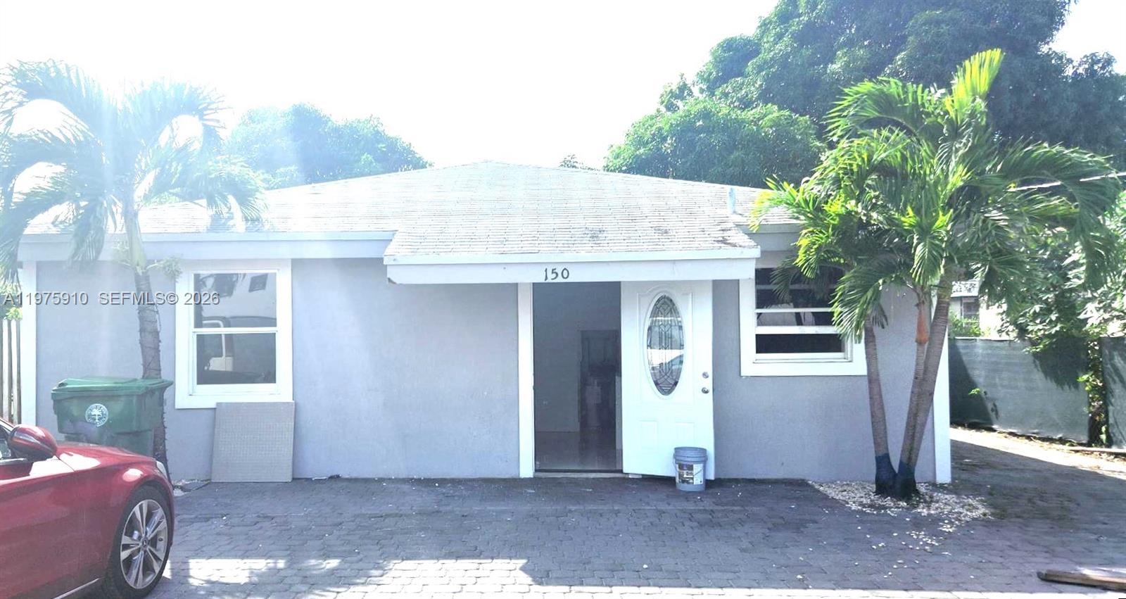 A single-story house with a gray exterior, a paved driveway, and two palm trees — 150 NW 17th Ct, Miami FL 33125, MIAMI, FL