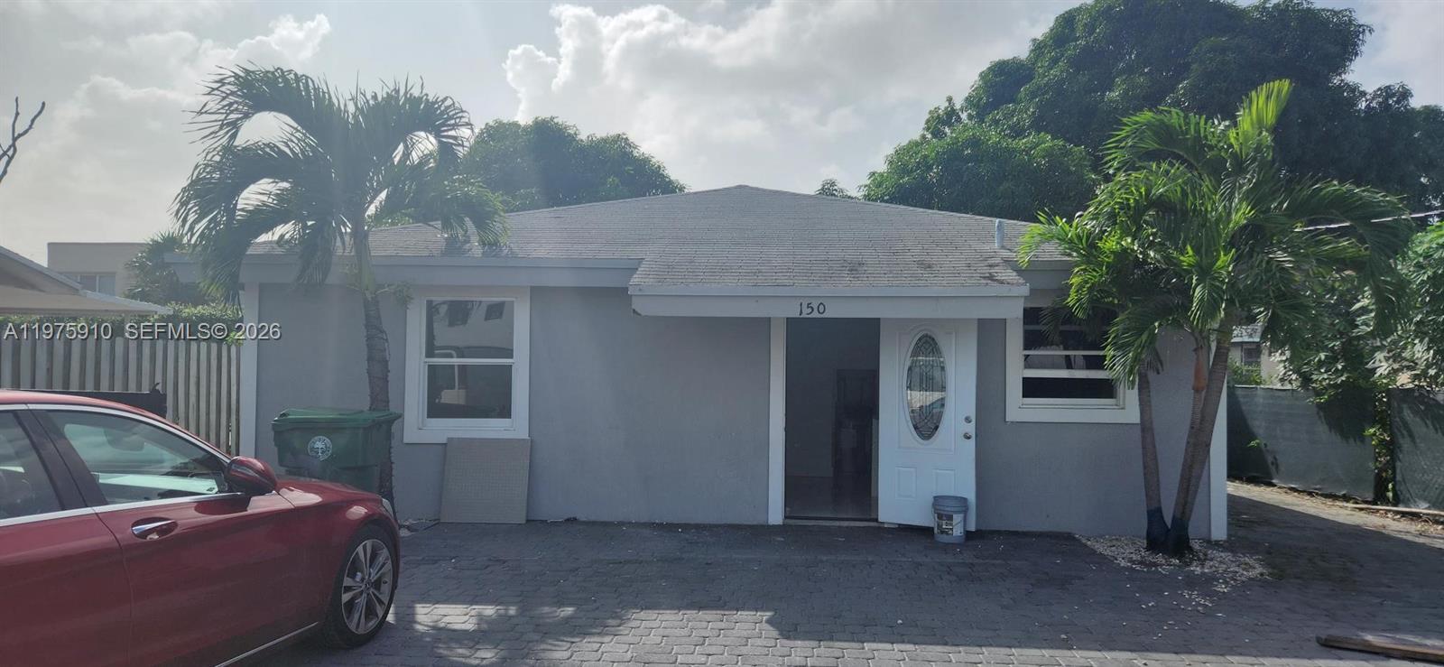 A single-story gray house with a white door and two palm trees in front — 150 NW 17th Ct, Miami FL 33125, MIAMI, FL
