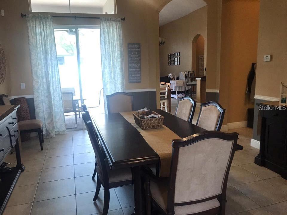 A dining room features a dark wood table, upholstered chairs, and a sliding glass door — 3009 JUNEBERRY TERRACE, OVIEDO, FL