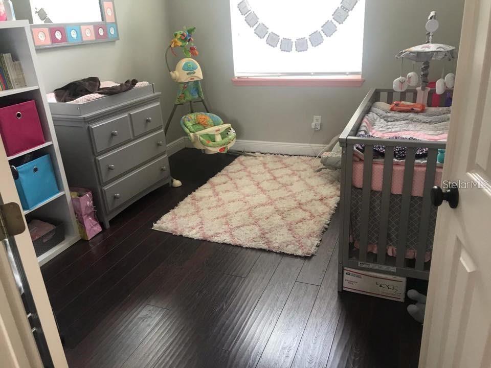 A nursery features a crib, a changing table, a baby swing, and a patterned rug — 3009 JUNEBERRY TERRACE, OVIEDO, FL