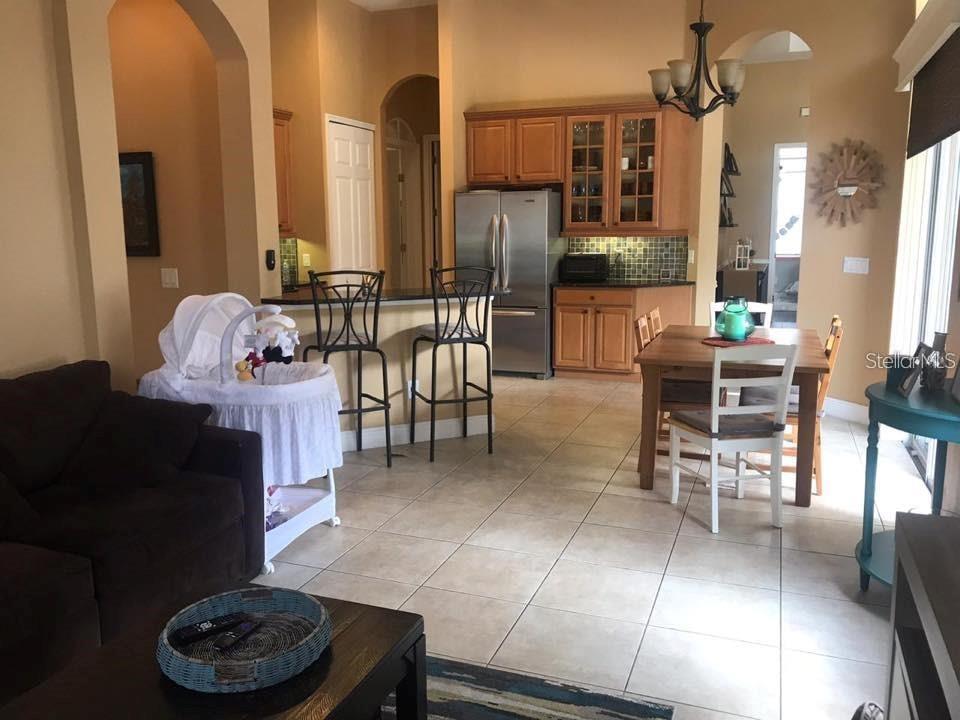 A kitchen with wood cabinets and stainless steel appliances opens to a dining area — 3009 JUNEBERRY TERRACE, OVIEDO, FL