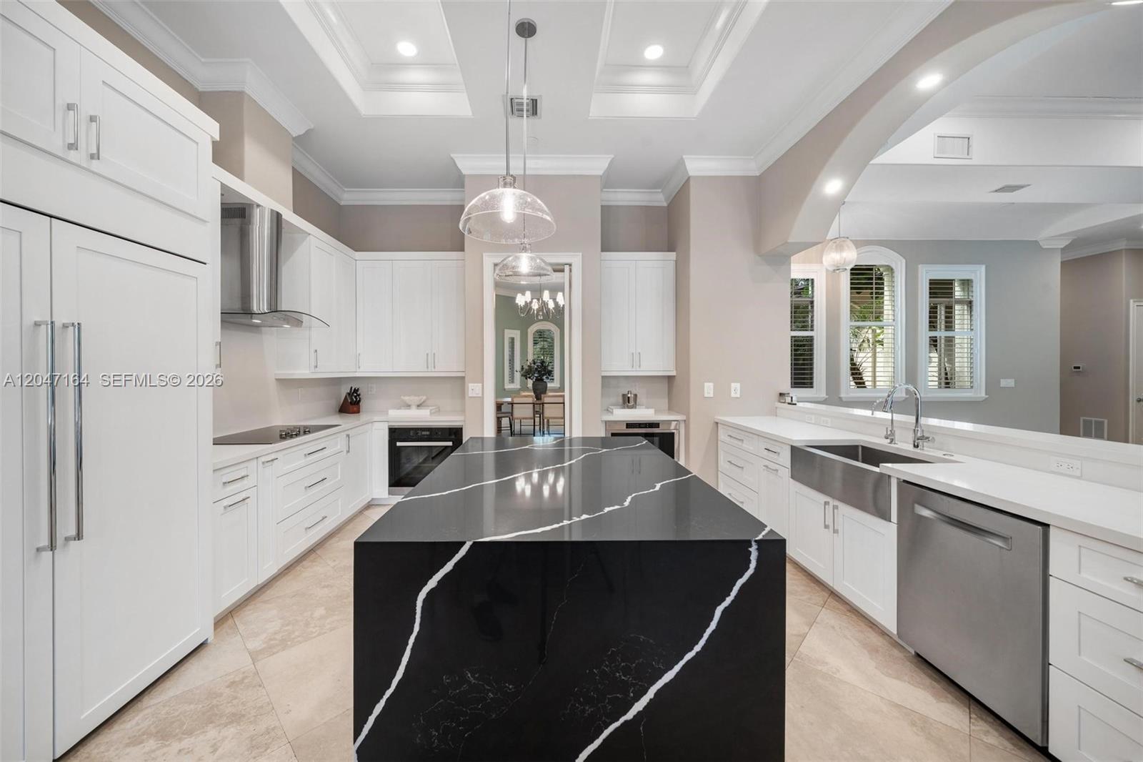 A modern kitchen features white cabinetry, a large black waterfall island, and stainless steel appliances — 6890 SW 94th St, Pinecrest FL 33156, PINECREST, FL