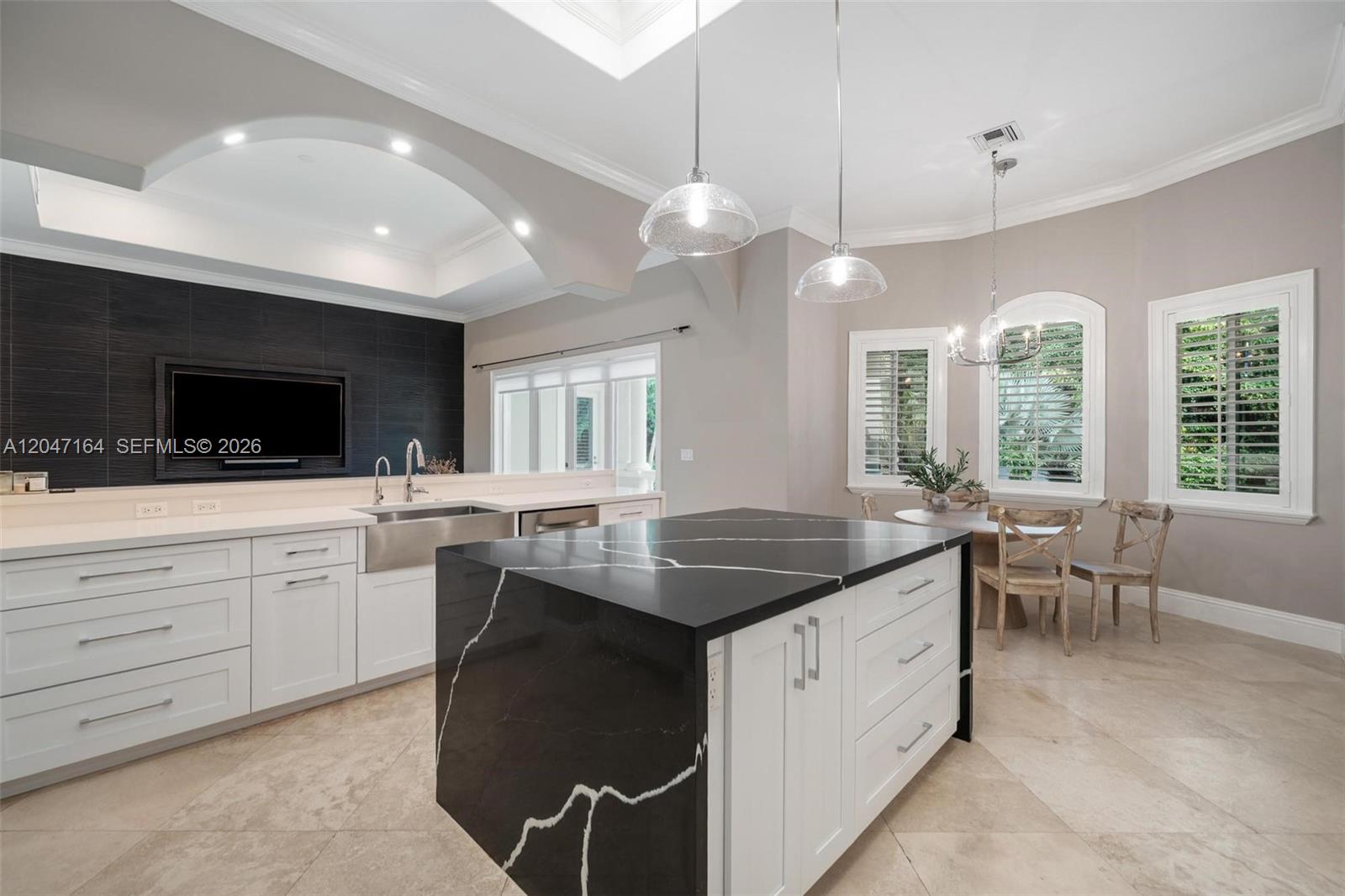 A kitchen features a black waterfall island, white cabinetry, and a dark tiled accent wall — 6890 SW 94th St, Pinecrest FL 33156, PINECREST, FL
