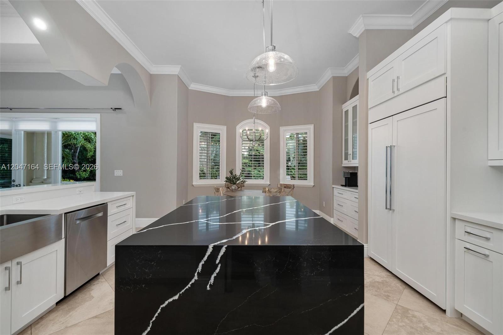 A kitchen features a large black quartz island with white veining and white cabinetry — 6890 SW 94th St, Pinecrest FL 33156, PINECREST, FL