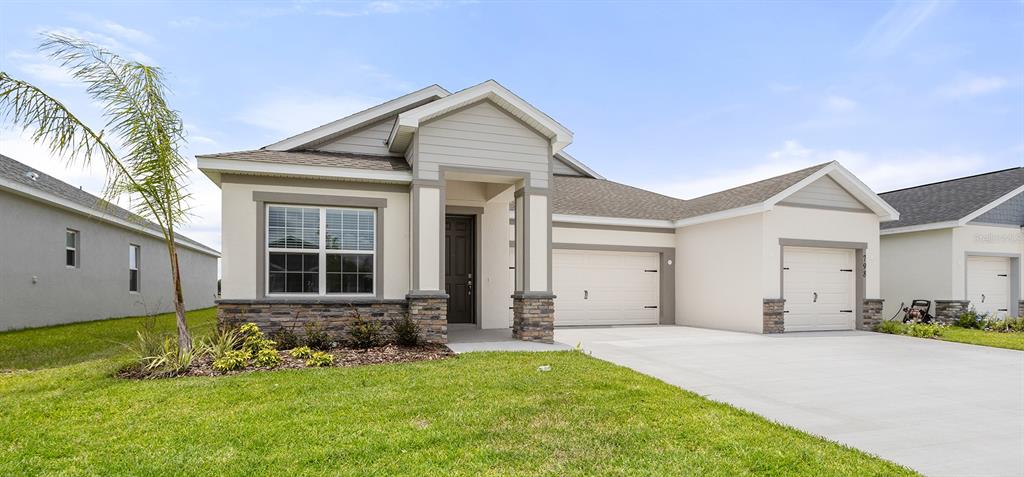 A single-story house with a stone-accented facade, two garage doors, and a front lawn — 798 CYPRESS CREEK RUN, ST CLOUD, FL