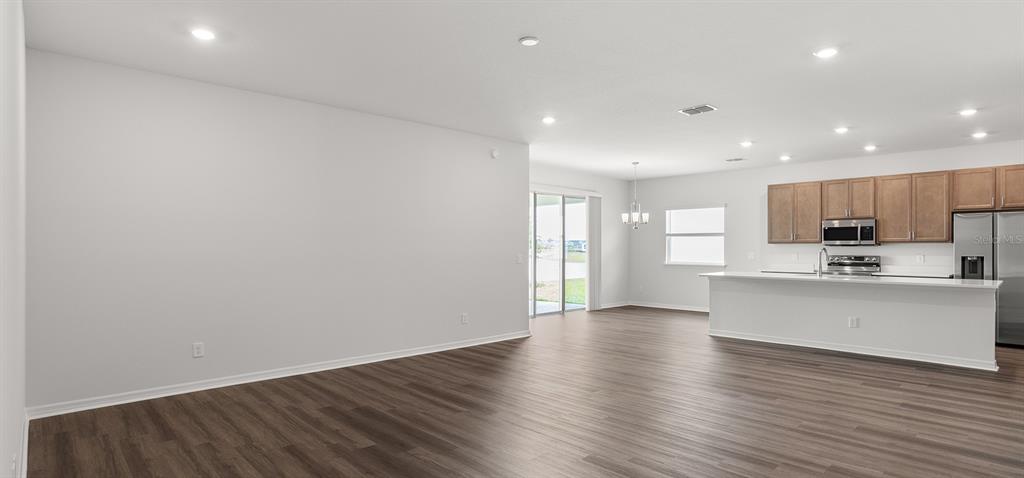 An open-concept living and kitchen area features light gray walls and dark wood-look flooring — 798 CYPRESS CREEK RUN, ST CLOUD, FL