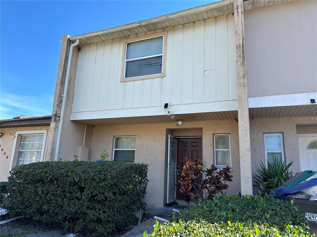 A two-story townhouse exterior features beige stucco, vertical siding, and a small front garden — 2513 RIO PINAR LAKES BOULEVARD, ORLANDO, FL