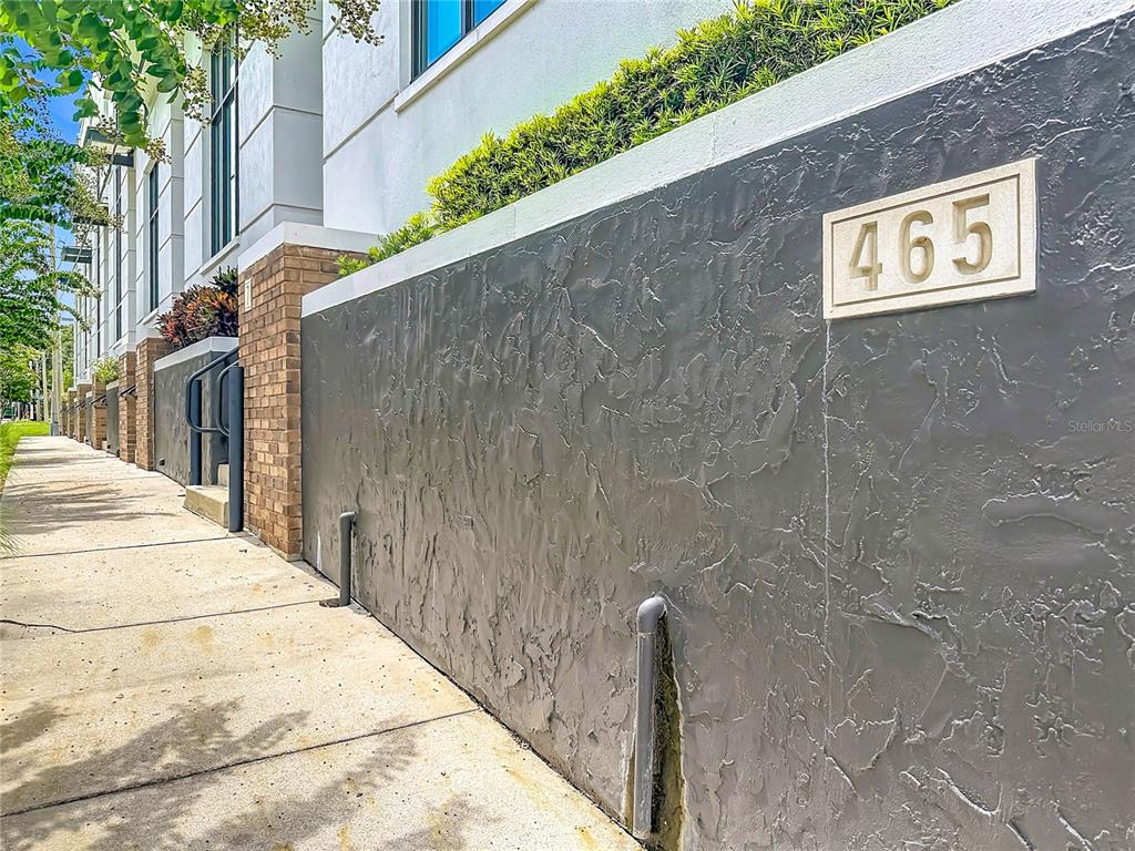 A low gray stucco wall with the number 465 sits beside a concrete sidewalk — 465 E SOUTH STREET UNIT 6, ORLANDO, FL