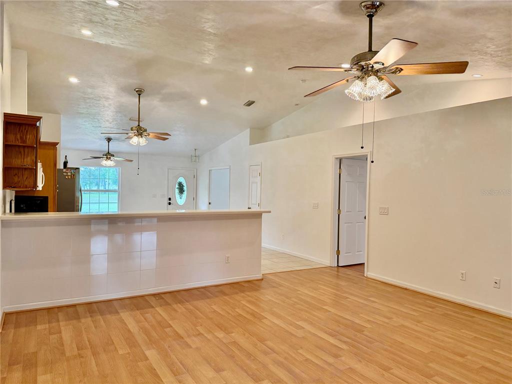 An open-concept living area features light wood flooring, a breakfast bar, and vaulted ceilings — 14190 NE 75TH STREET, BRONSON, FL