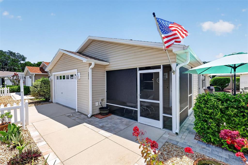 A single-story house with beige siding, a garage, and a screened-in porch under a blue sky — 356 KATHERINE PLACE, THE VILLAGES, FL
