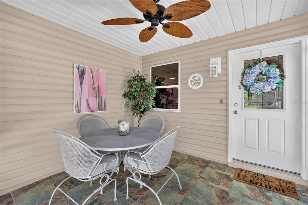 A covered patio features a round metal table with four chairs, tile flooring, and siding — 356 KATHERINE PLACE, THE VILLAGES, FL