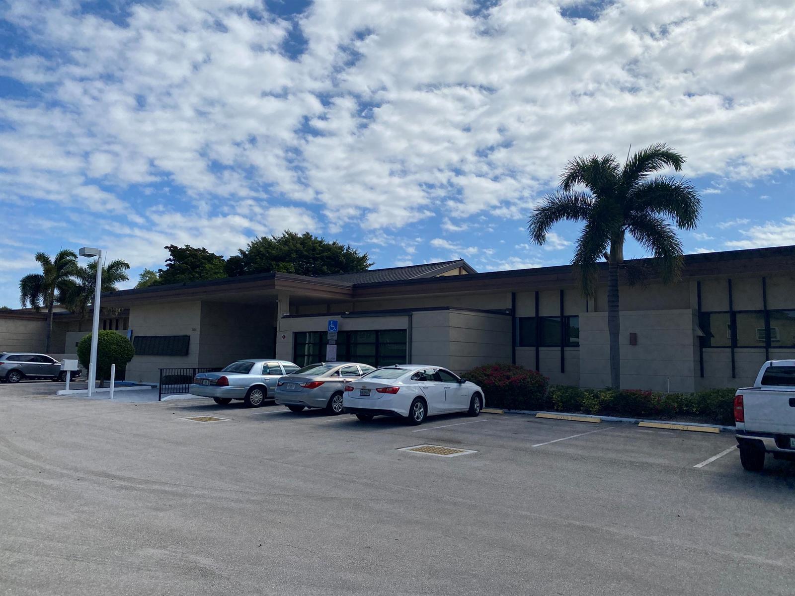 A single-story commercial building with a parking lot and palm trees under a cloudy sky — 7205 W Atlantic Boulevard, Margate FL 33063, MARGATE, FL