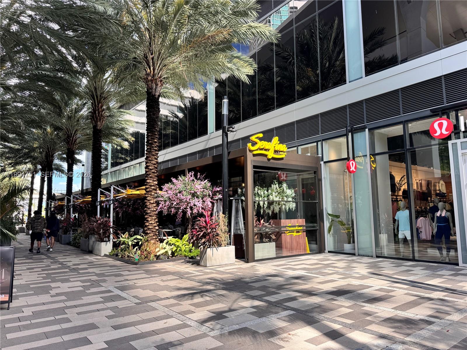 An outdoor restaurant patio sits next to a storefront with a large glass facade — 159 NE 6 # 4508, Miami FL 33132, MIAMI, FL