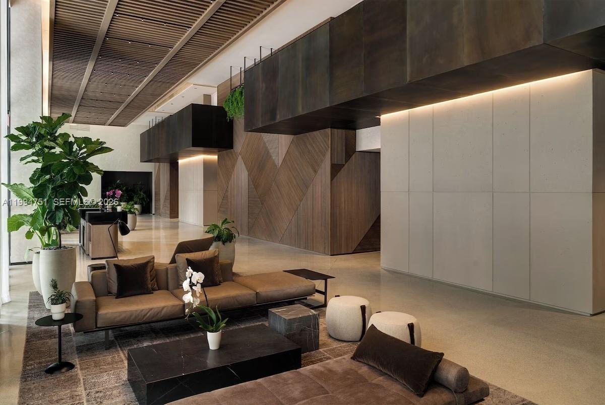 A modern lobby features a brown sectional sofa, wood-paneled walls, and a slatted ceiling — 159 NE 6 # 4508, Miami FL 33132, MIAMI, FL