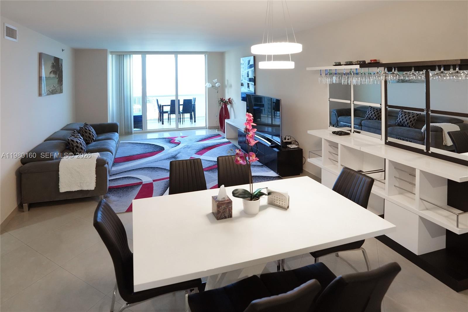 A modern living and dining area features a white table, gray sofa, and balcony view — 1830 S Ocean Dr # 4111, Hallandale Beach FL 33009, HALLANDALE BEACH, FL