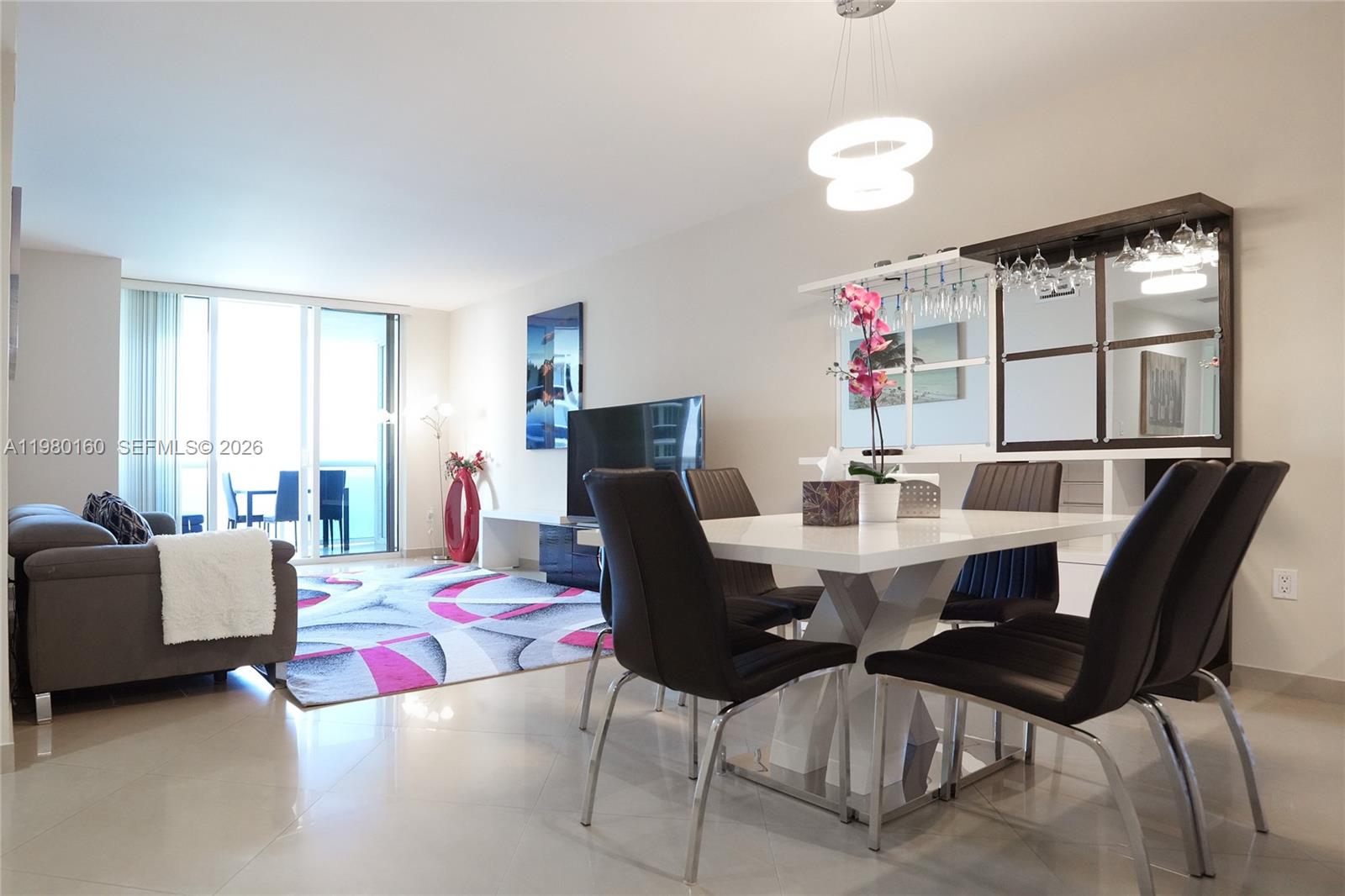 A dining area with a white table and black chairs sits before a living room — 1830 S Ocean Dr # 4111, Hallandale Beach FL 33009, HALLANDALE BEACH, FL