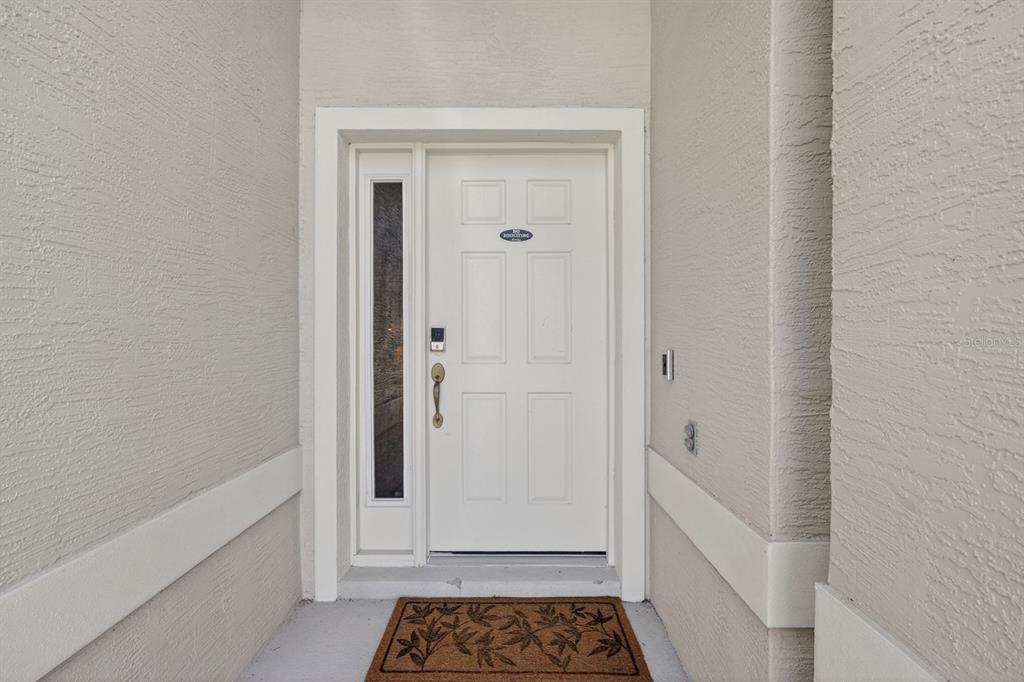 A white front door with a side window and a brown patterned doormat — 5466 WARD LAKE DRIVE, PORT ORANGE, FL