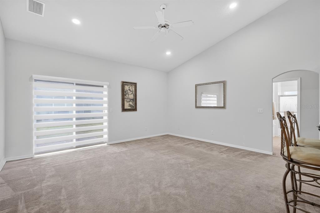 A carpeted living room features a ceiling fan, sliding glass doors, and a framed mirror — 5466 WARD LAKE DRIVE, PORT ORANGE, FL