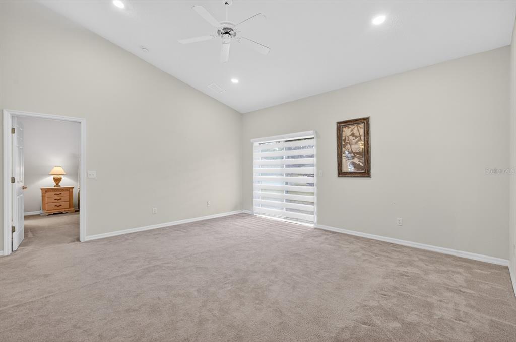 A carpeted bedroom with a vaulted ceiling, a ceiling fan, and a sliding glass door — 5466 WARD LAKE DRIVE, PORT ORANGE, FL