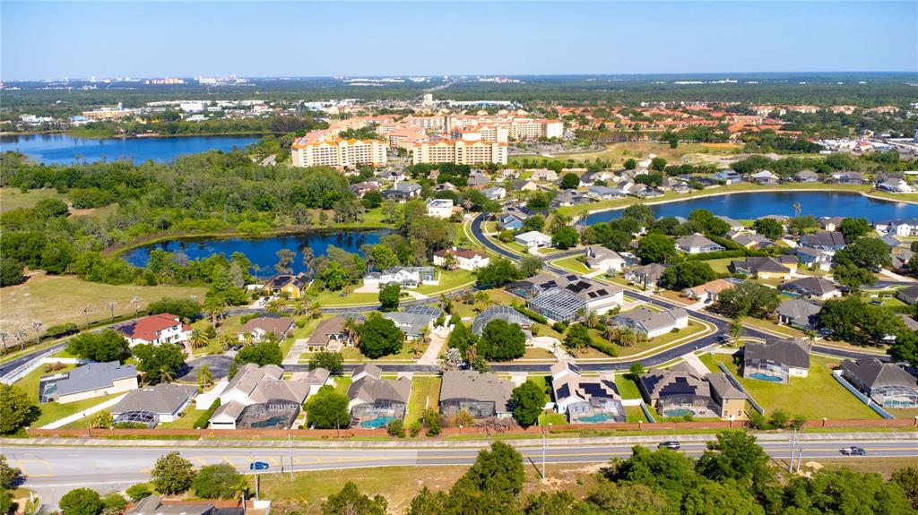 An aerial view shows a suburban neighborhood with houses, swimming pools, and nearby lakes — 8032 ACADIA ESTATES COURT, KISSIMMEE, FL
